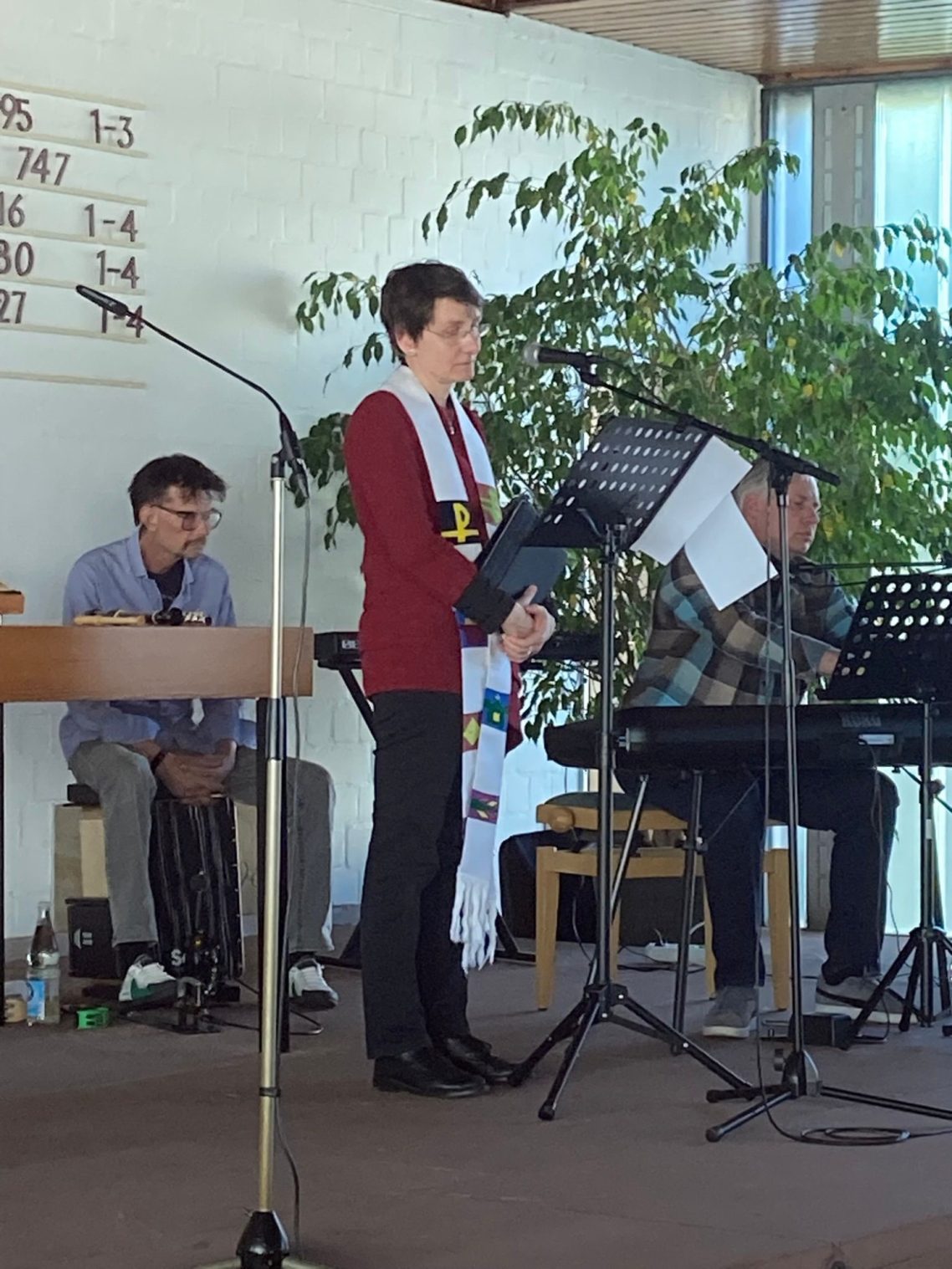 Gedenkgottesdienst am 29. April 2026 Dr. Maresa Biesterfeld spricht auf einer Bühne, im Hintergrund Musiker und Pflanzen.
