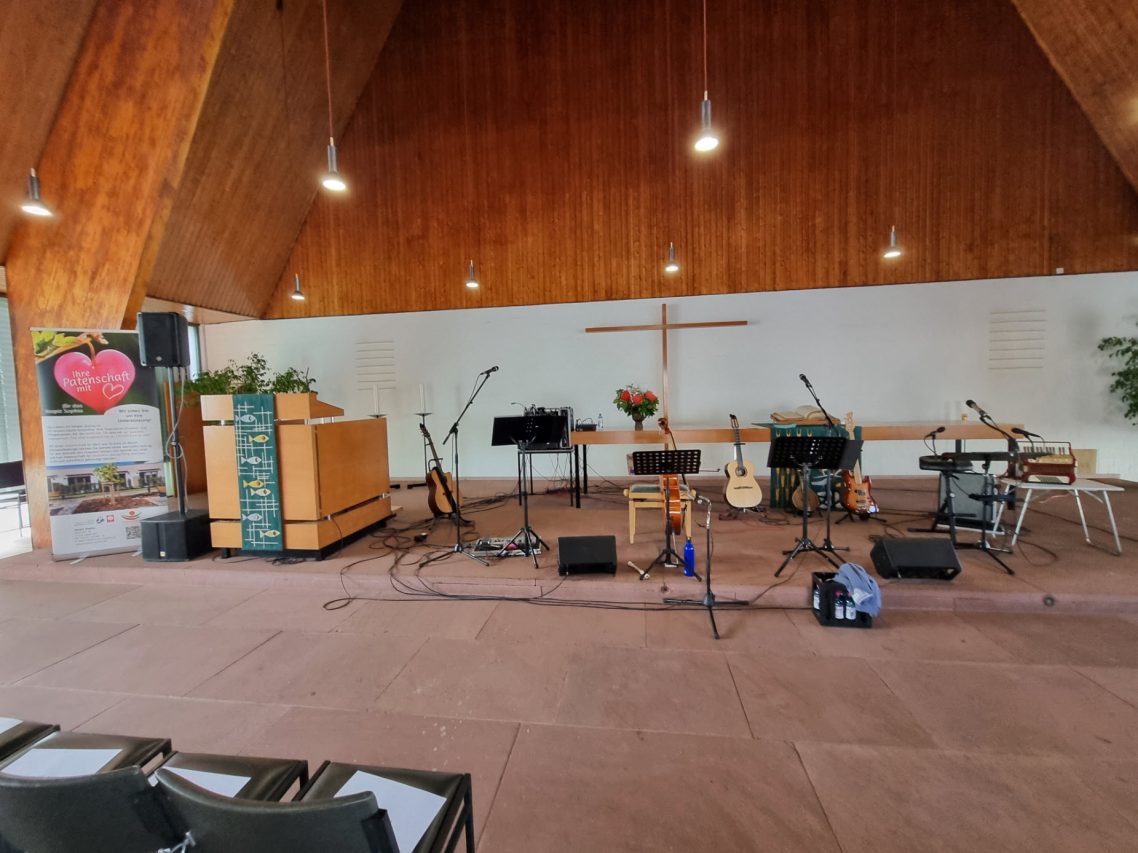 Benefizkonzert für das Hospiz Sophia - "Übers Meer - Von Meerbusen und Seesäcken" Bühne in einer Kirche mit Musikinstrumenten und Mikrofonen, bereit für eine Veranstaltung.