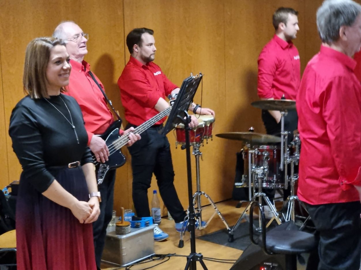 Benefizkonzert der Rhein-Nahe Big Band Die Rhein-Nahe Big Band in roten Hemden, bereit zur Zugabe, mit Instrumenten im Hintergrund.