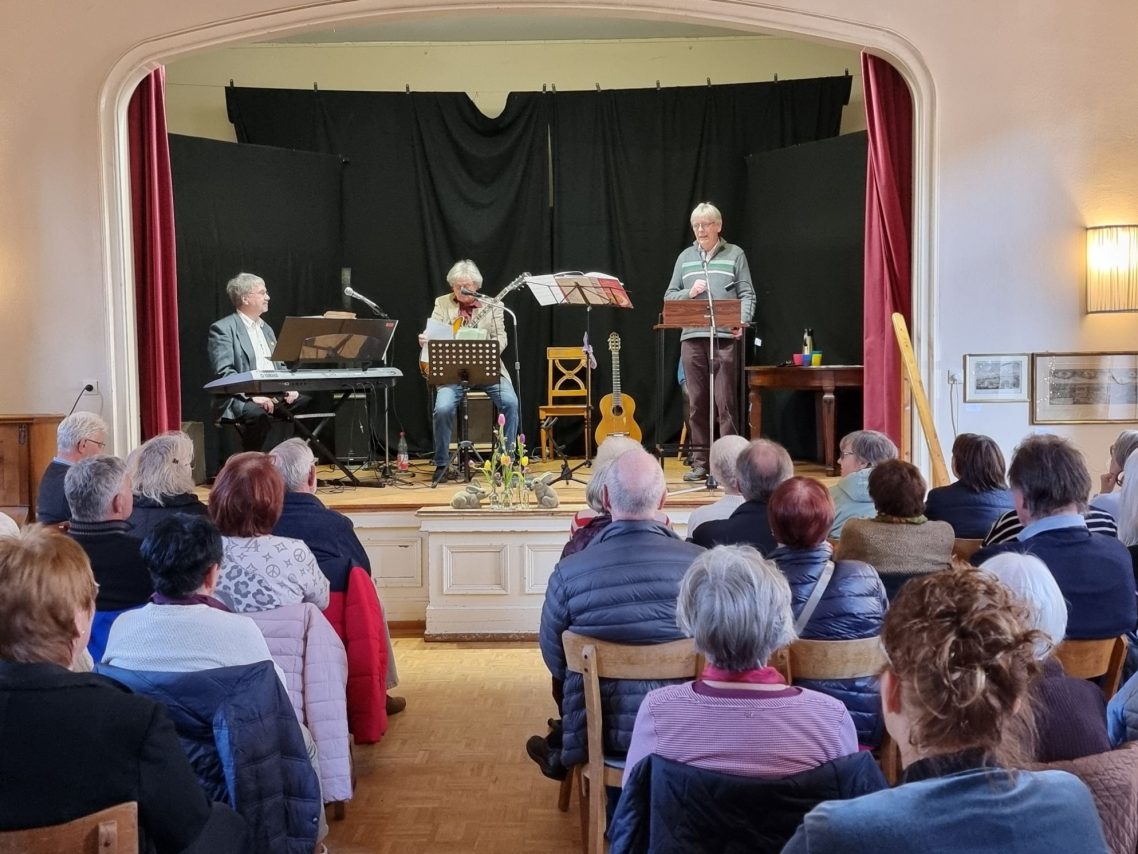 Soirée im Haus Burggarten Drei Musiker treten auf einer Bühne vor einem Publikum auf.